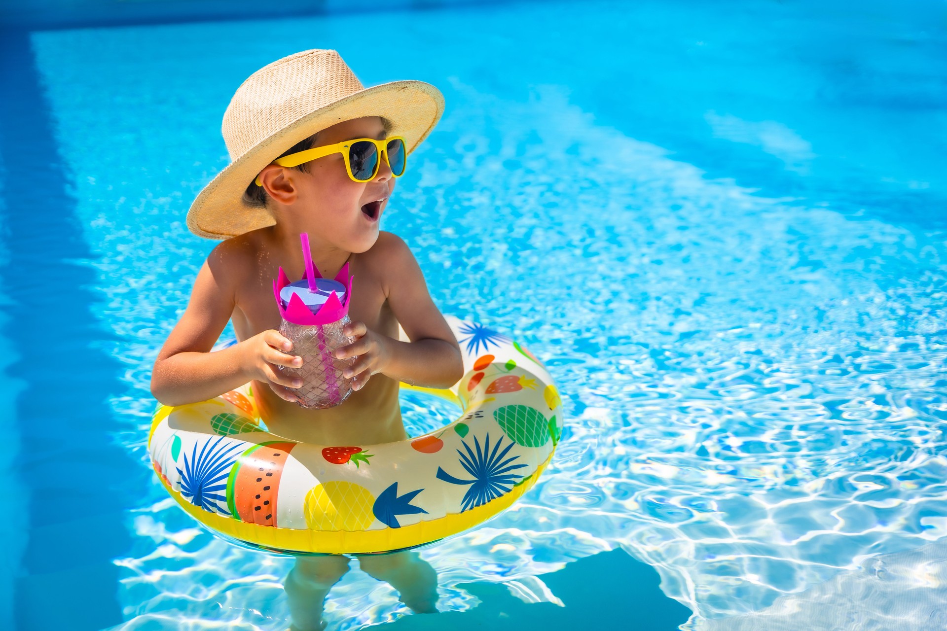 Playful kid in sun hat and sunglasses on a pool
